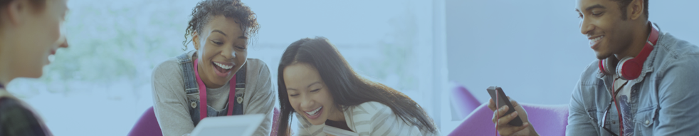 Group of students laughing and looking and phones and computers